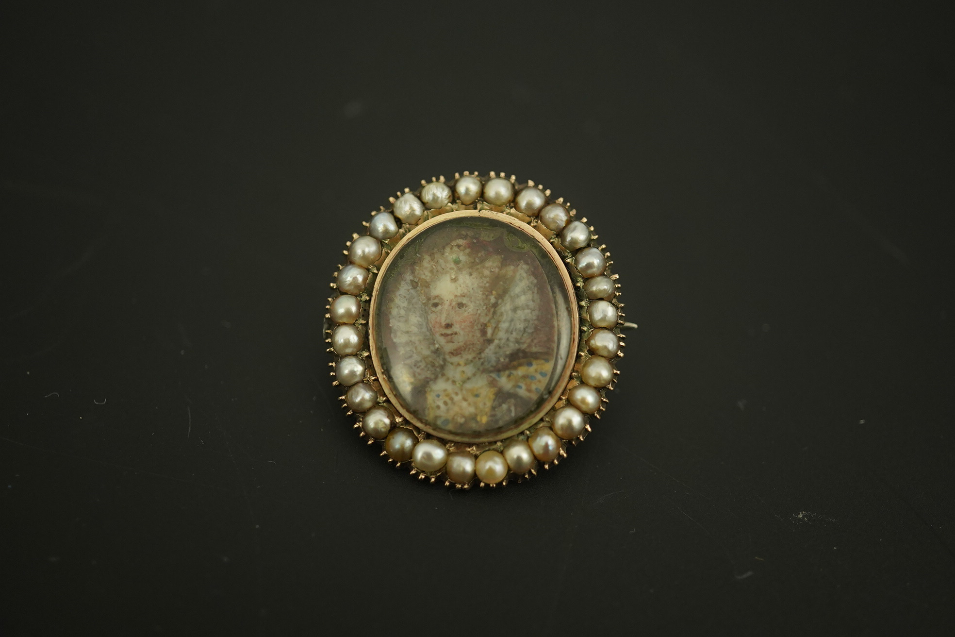 An early 19th century yellow metal and split pearl mounted oval miniature portrait pendant brooch